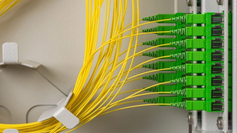 A specialist technician performing fiber optic fusion splicing using advanced equipment in a modern setting.