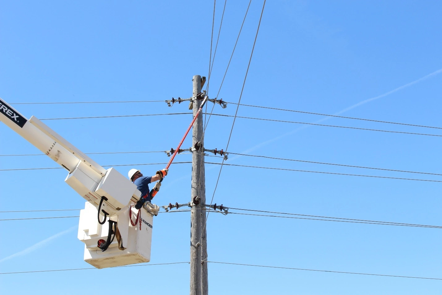 Aerial fiber optic cabling installation on utility poles using ADSS cables.